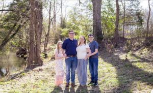 Family photo of four people outdoors.